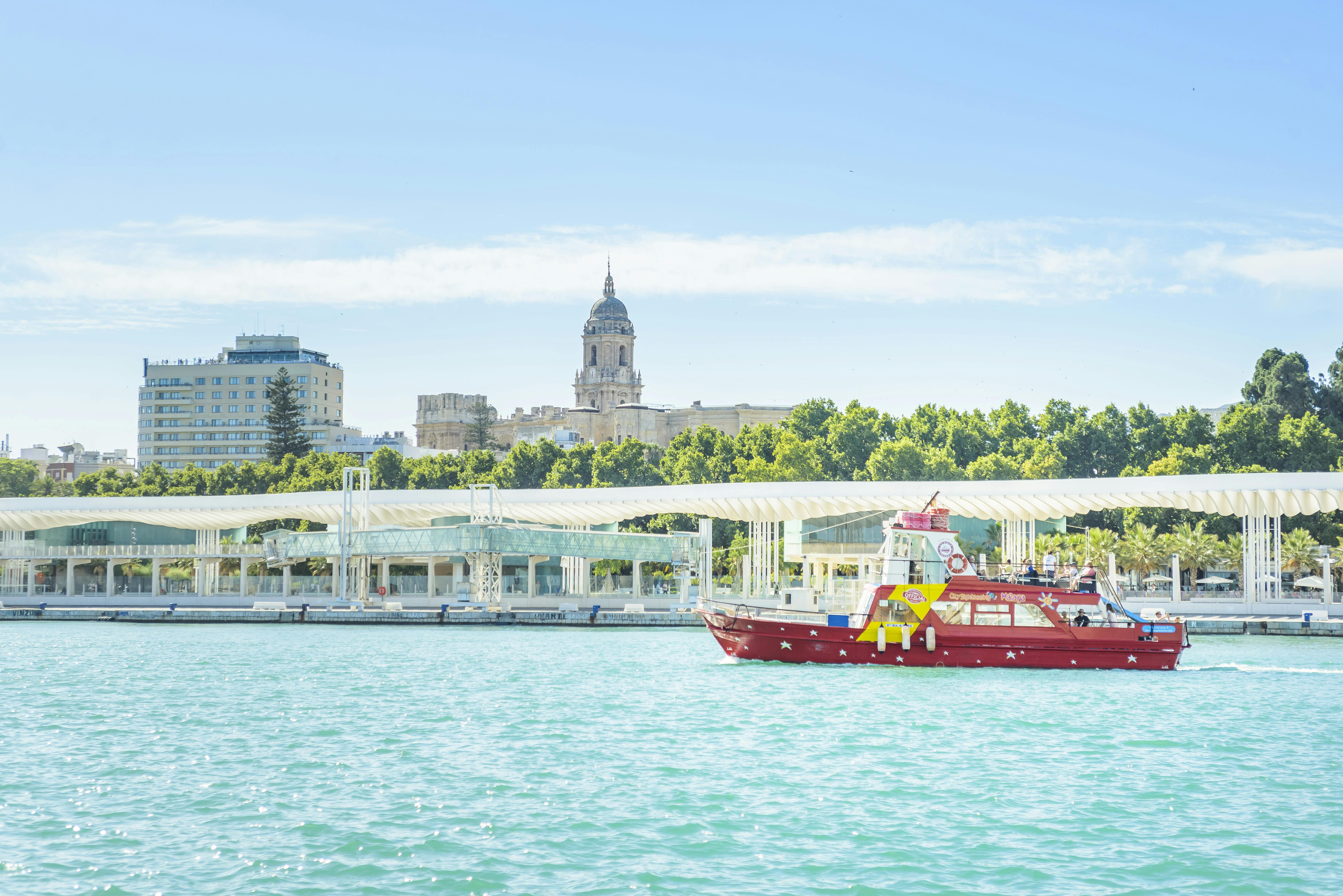 A red boat on turquoise water with a white-covered dock, leafy trees, and a historic building with a dome in the background.