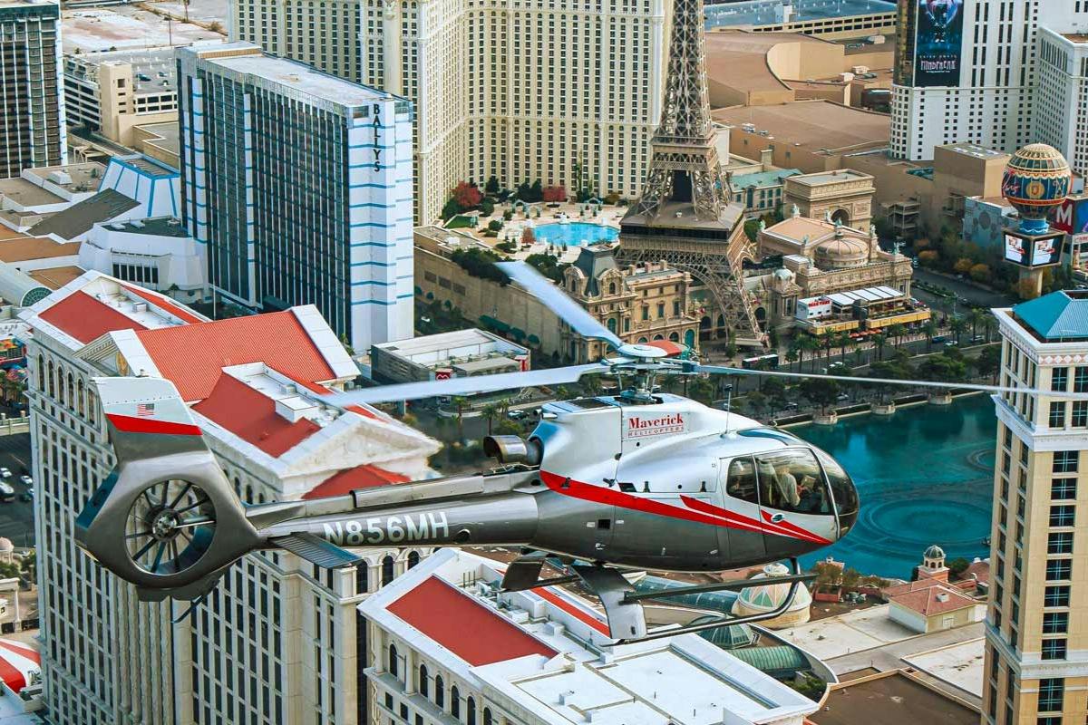 A helicopter flying above a cityscape with iconic buildings, including a replica of the Eiffel Tower.