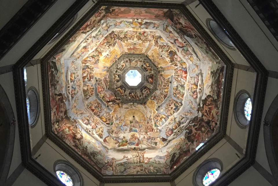 Intricately painted domed ceiling depicting numerous figures in various scenes, surrounded by arched windows.