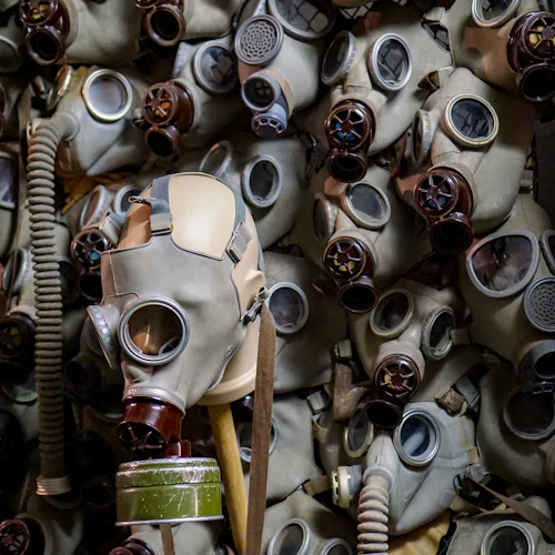 En samling gasmasker, med en framträdande i förgrunden bland många andra på väggen bakom.