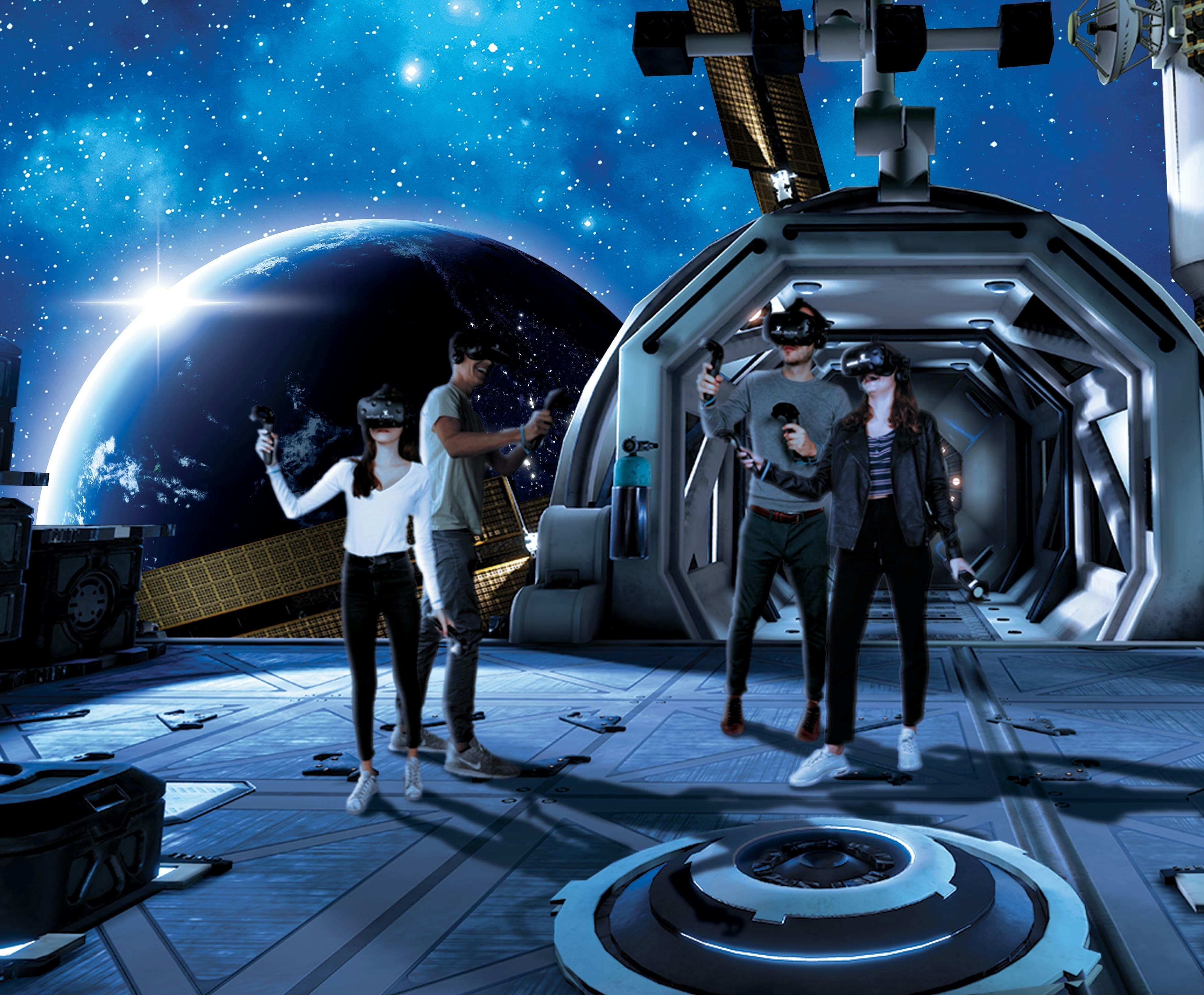 Four people wearing VR headsets interact in a space station environment with Earth and stars visible in the background.