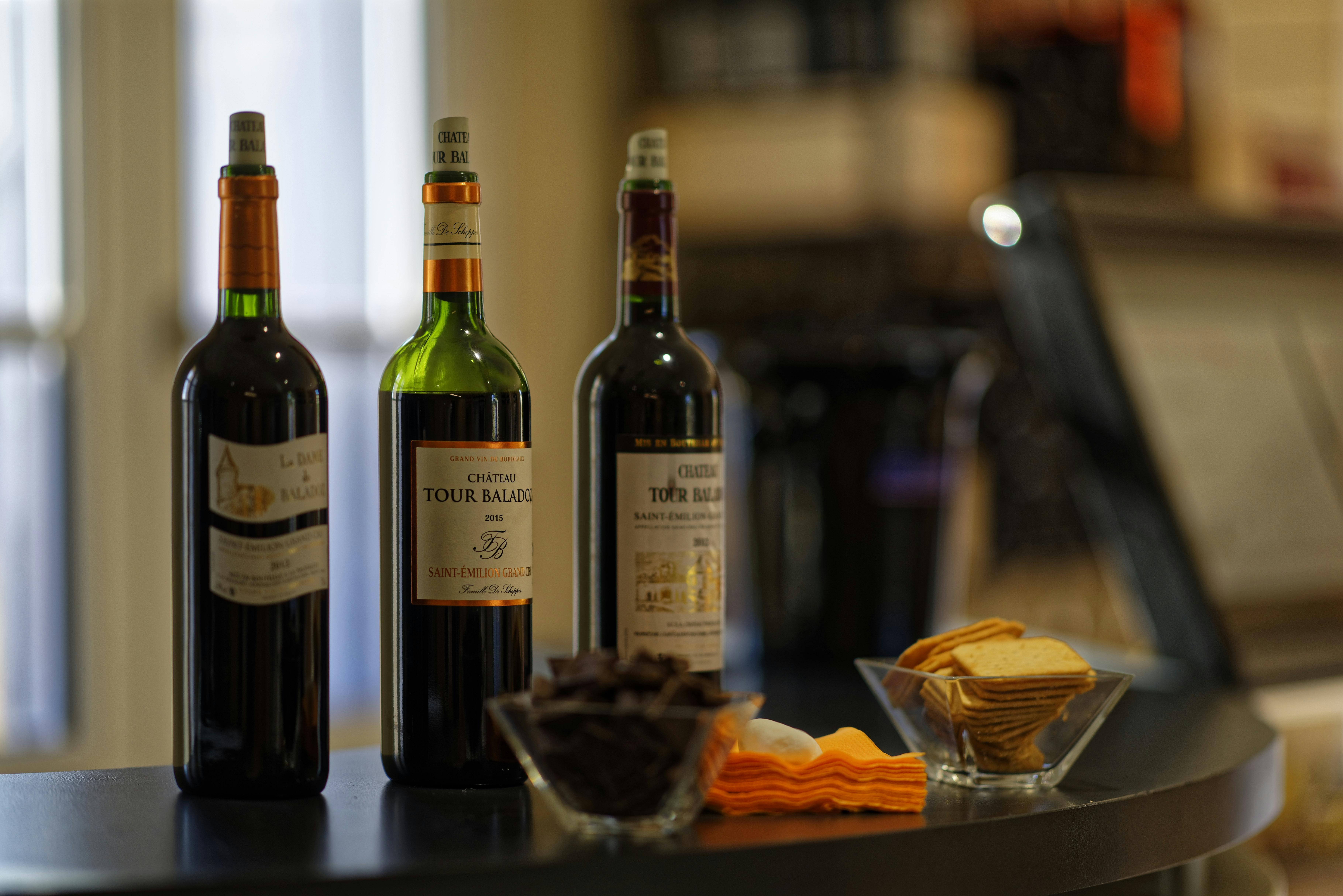 三瓶葡萄酒，两碗小吃，在昏暗的环境中将餐巾折叠在黑色的表面上。