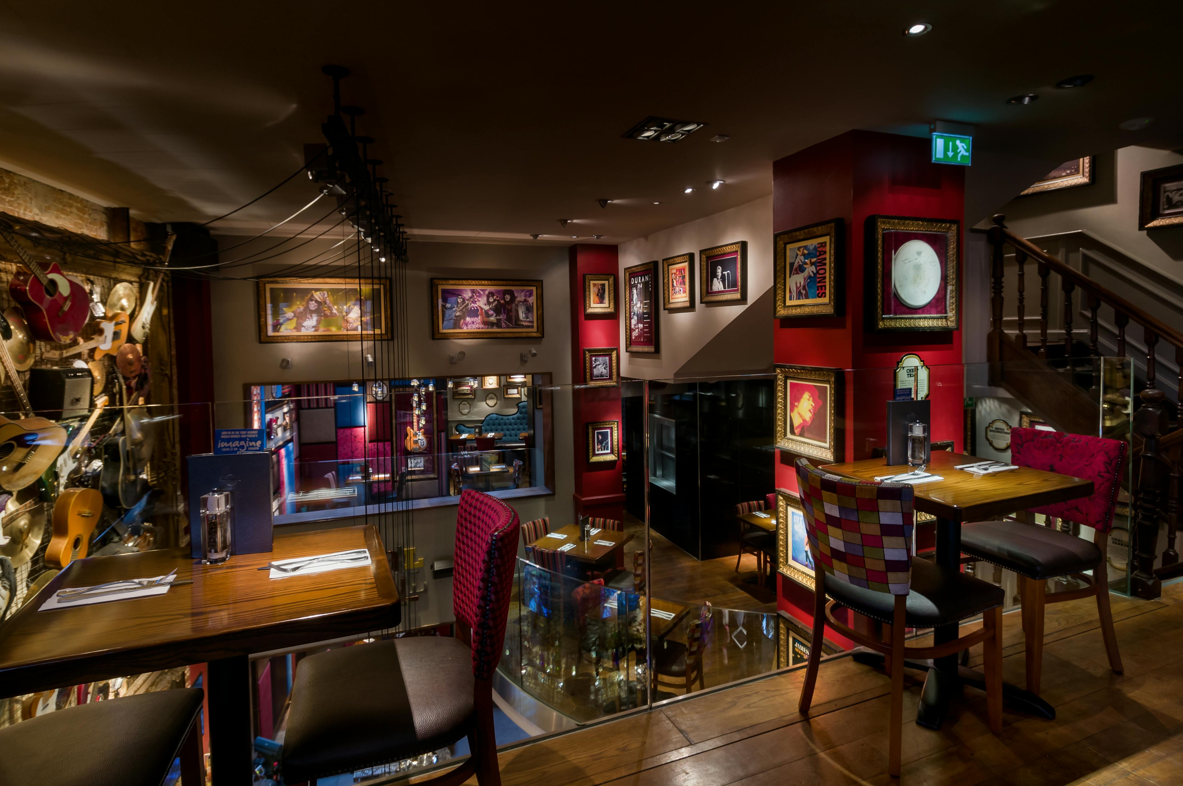 Interiér restaurace s zarámovanými obrazy na stěnách, prostřenými stoly pro dva a eklektickým posezením v tlumeně osvětlené, útulné atmosféře.