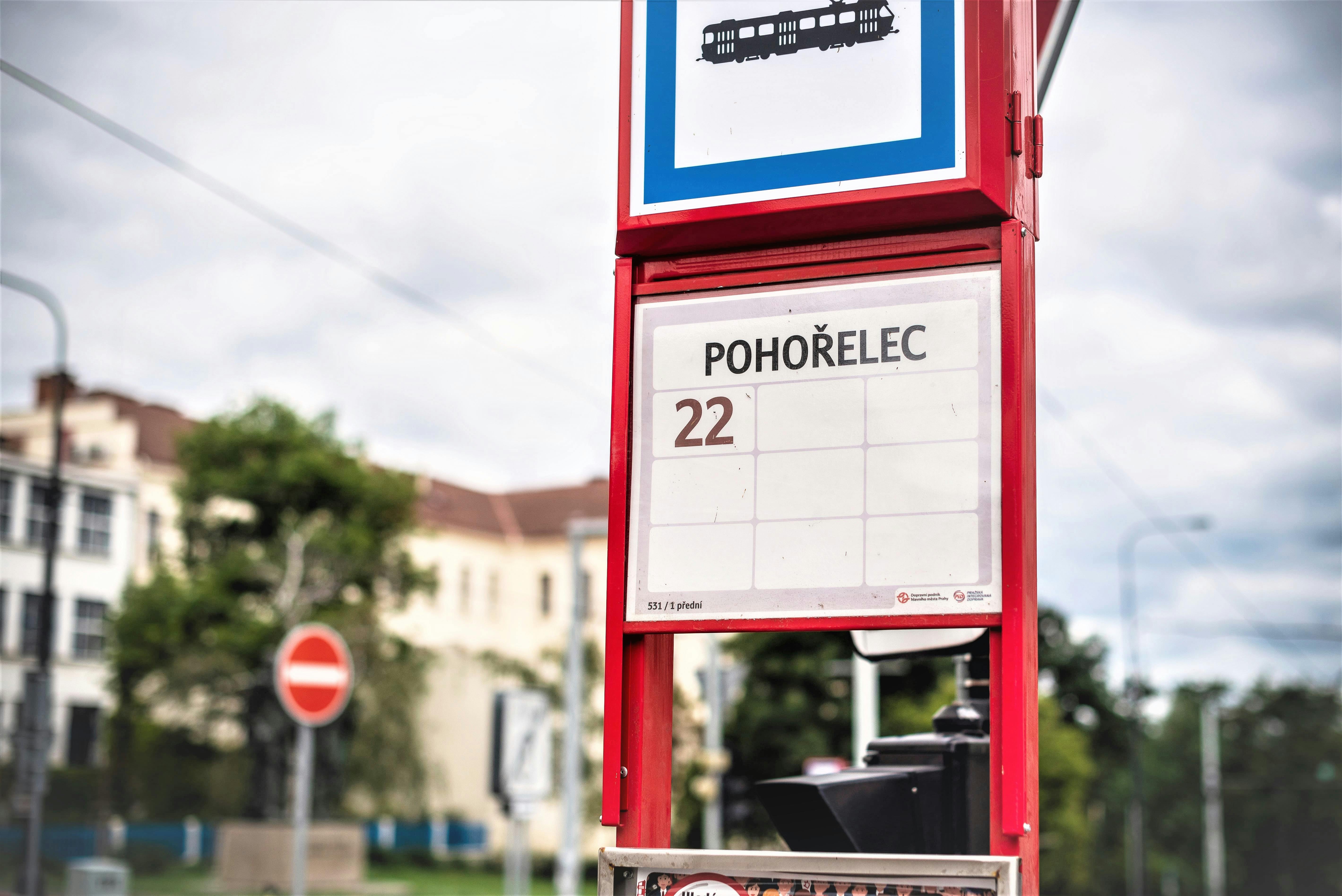 建物と木々を背景に、「ポホレック」と22番を表示する赤い路面電車停留所の標識。