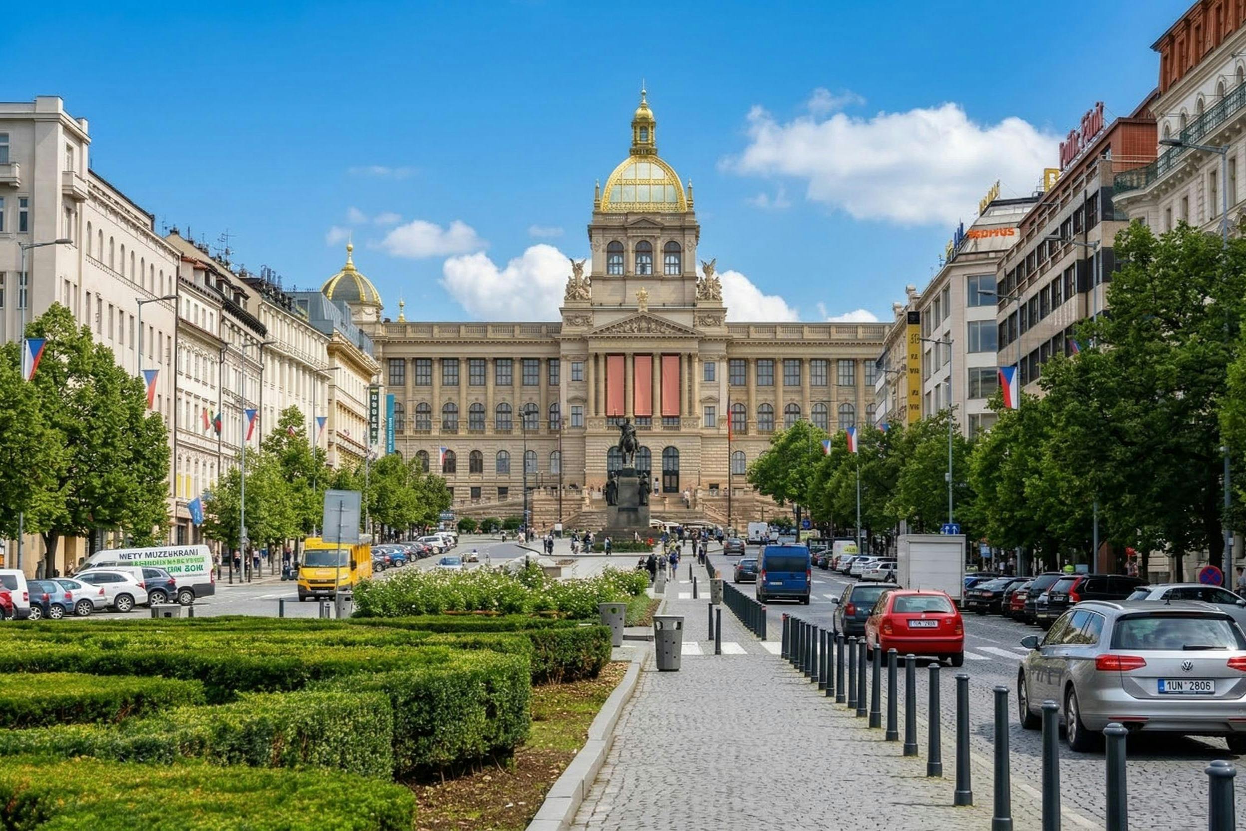 도시 광장에 황금색 돔이 있는 웅장한 건물로 나무, 자동차, 구름이 낀 푸른 하늘 아래 사람들로 둘러싸여 있습니다.