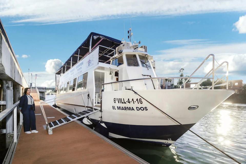 A large boat named "El Miarma Dos" docked at a pier on a sunny day. Banners are displayed on the boat.