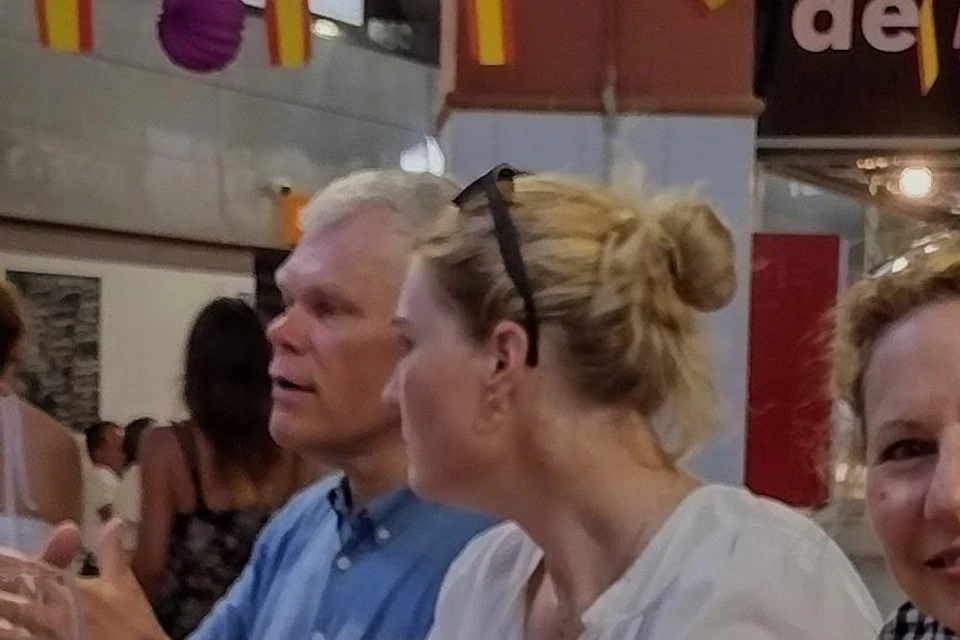 People sitting at a table enjoying food and drinks in a lively, colorful restaurant decorated with small flags and paper lanterns.