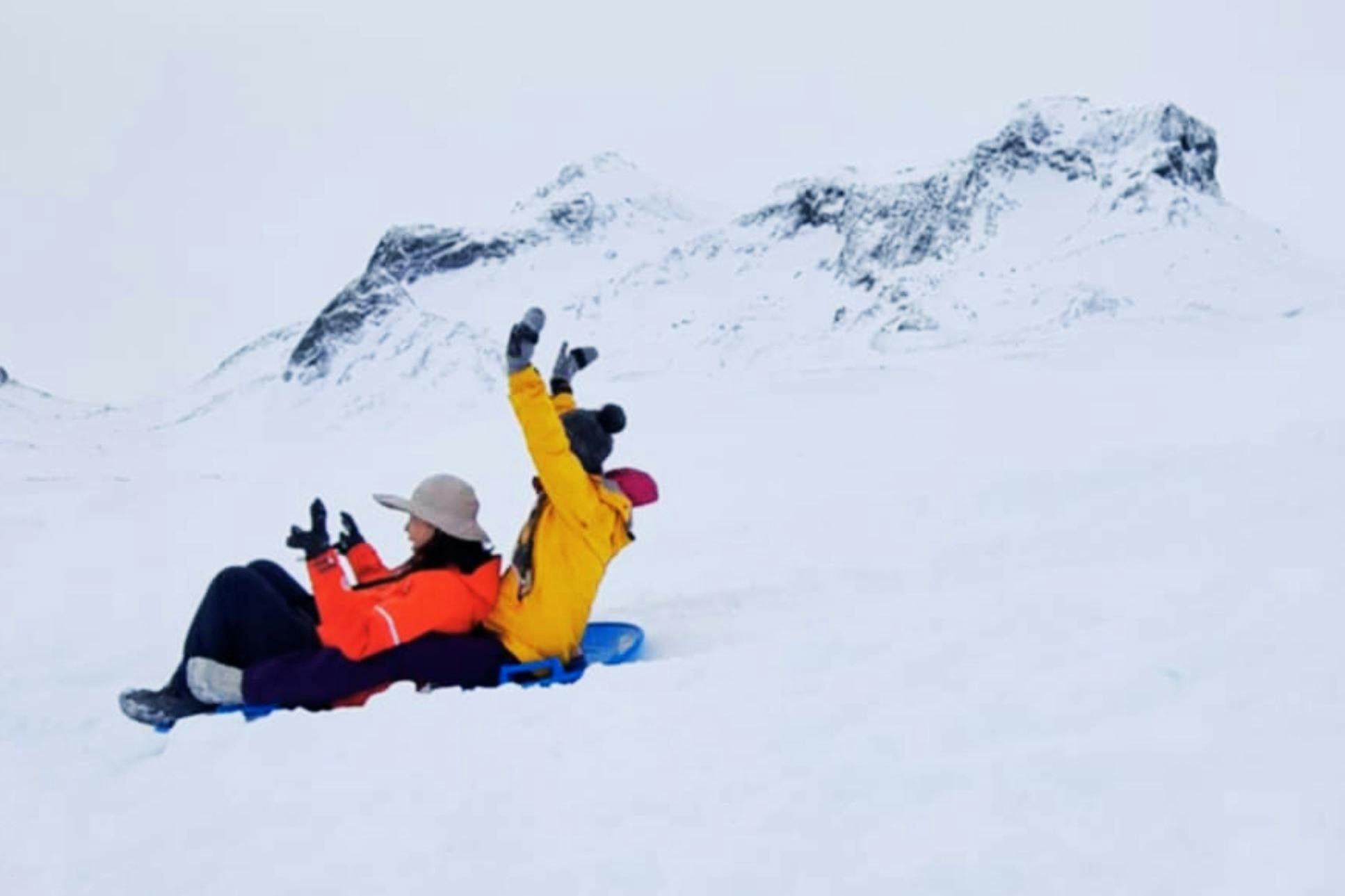 Άνθρωποι που κατεβαίνουν με έλκηθρο ένα χιονισμένο λόφο στον Παγετώνα