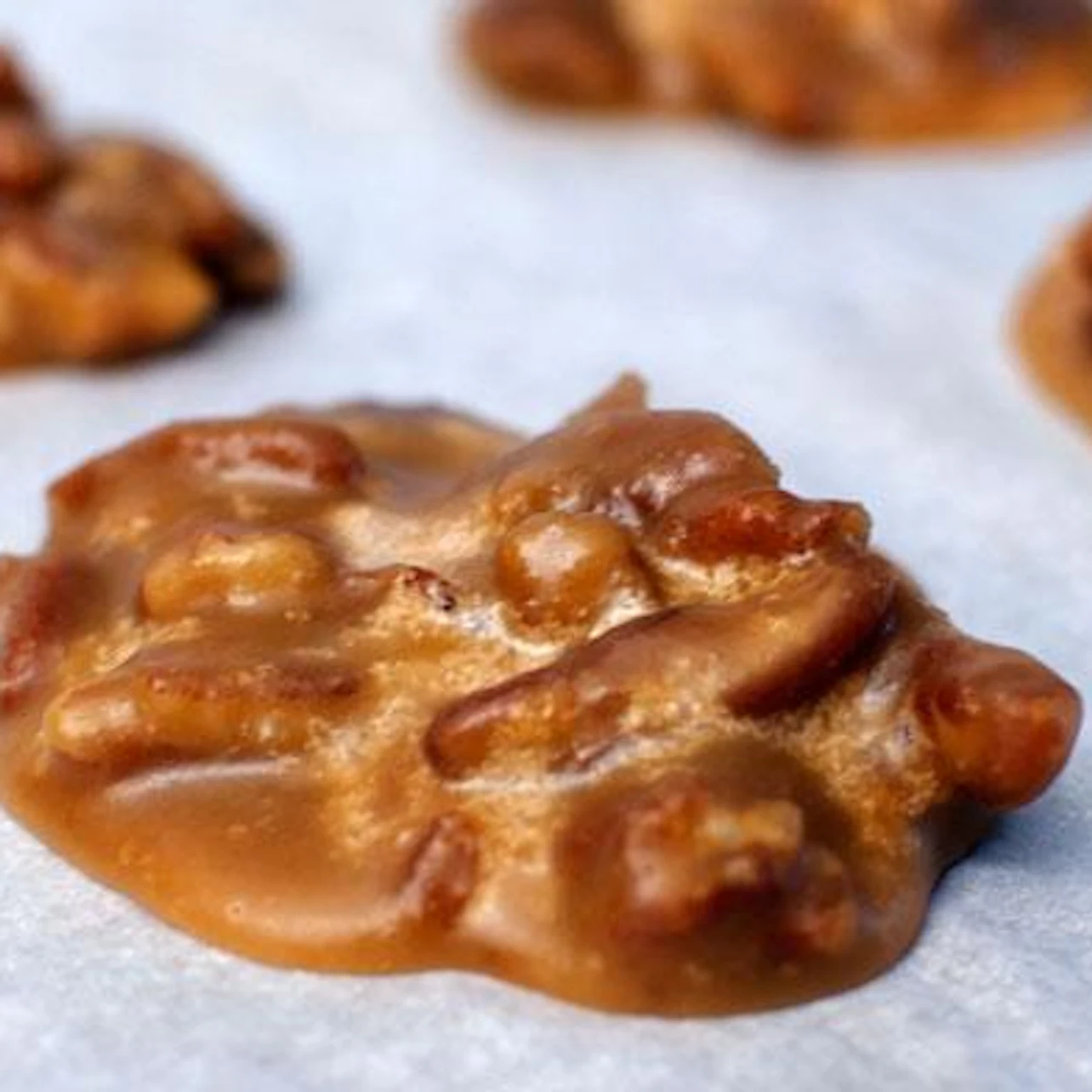 Close-up of pecan praline candies resting on parchment paper.