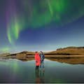Proprietários na paisagem da Islândia com a aurora boreal
