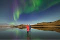 Proprietários na paisagem da Islândia com a aurora boreal