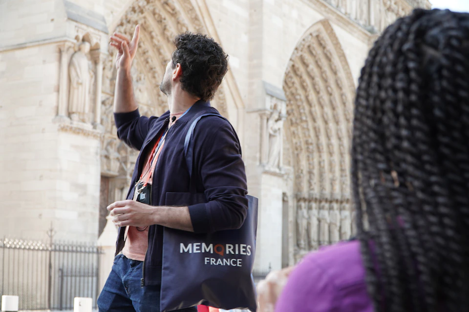 Guide pointing out details on the facade of Notre Dame Cathedral