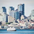 Das Schiff Argosy Cruise fährt entlang der Uferpromenade mit der Skyline von Seattle und dem Seattle Great Wheel im Hintergrund.
