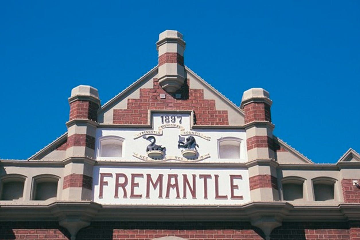 Een gevel met het woord "FREMANTLE" en het jaartal "1897", voorzien van decoratieve details en een blauwe lucht.