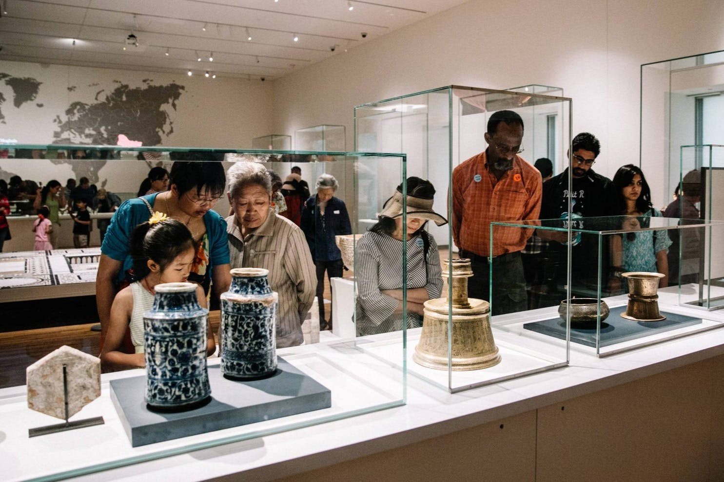 Lidé si prohlížejí starověké artefakty uvnitř skleněných vitrín v muzejní galerii.