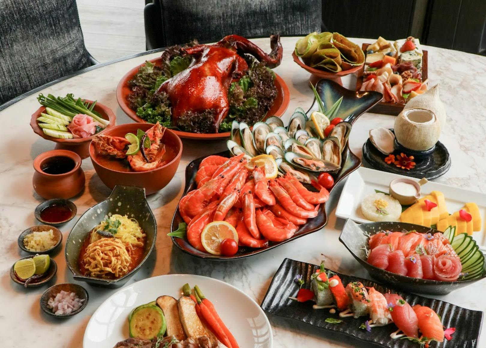 A table set with a variety of dishes, including seafood, roast duck, sushi, and other colorful gourmet items.