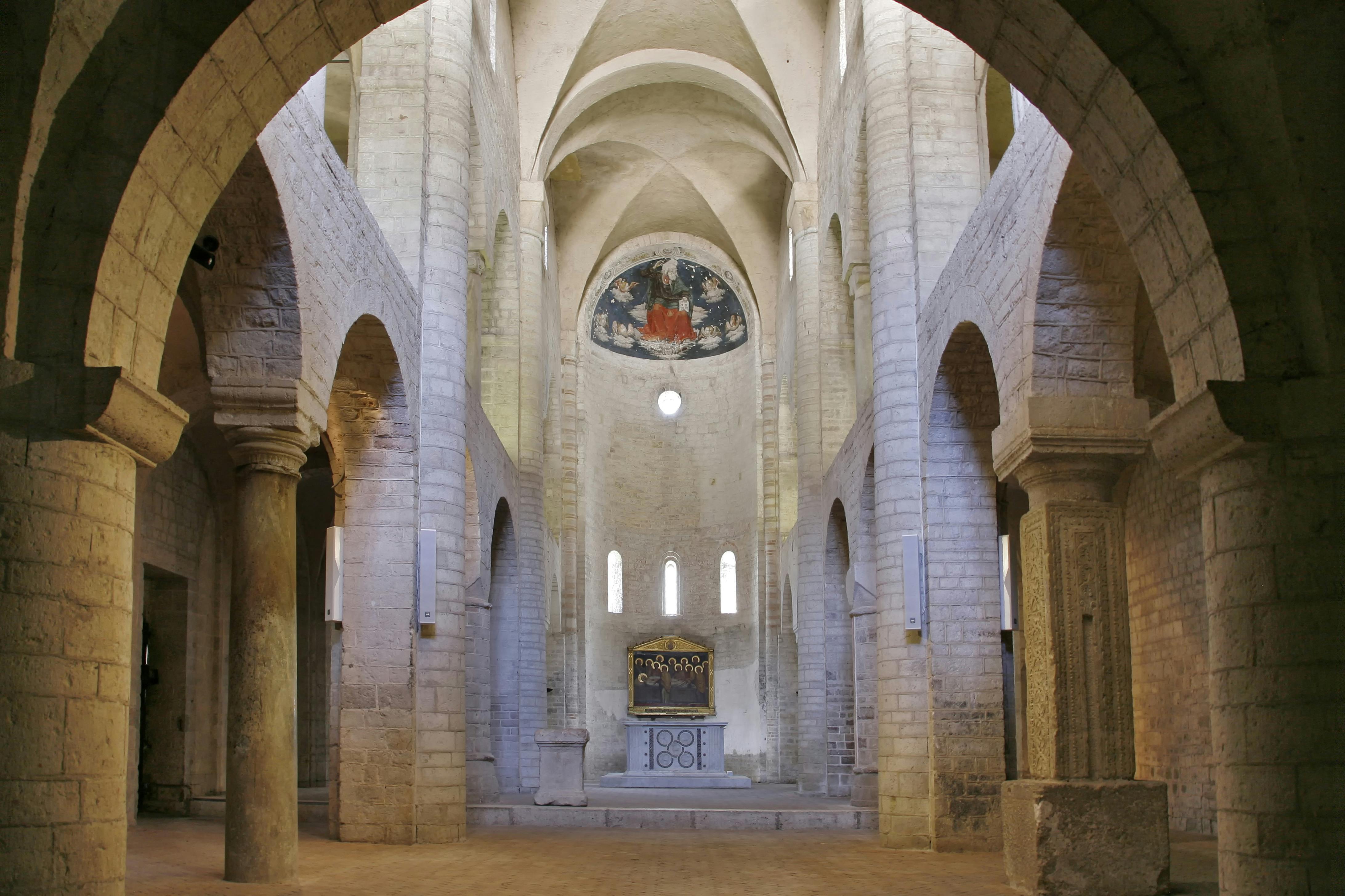 Εσωτερικό πέτρινης εκκλησίας με ψηλές καμάρες, θολωτές οροφές, περίτεχνο βωμό και τοιχογραφία από πάνω. Δεν παρευρίσκονται άτομα.