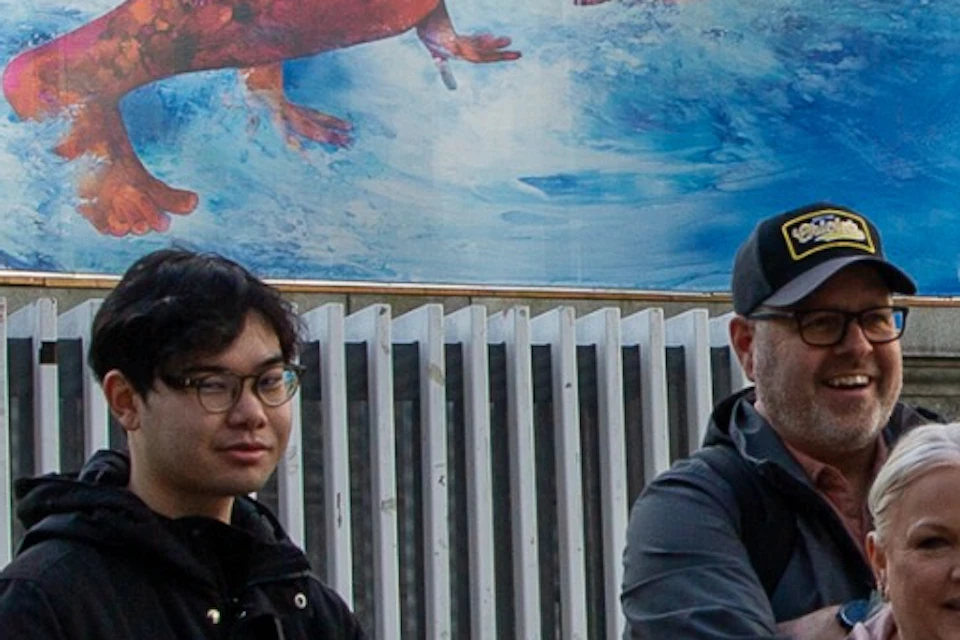 A group of people gathered in front of an old building with a large mural depicting a person swimming underwater.