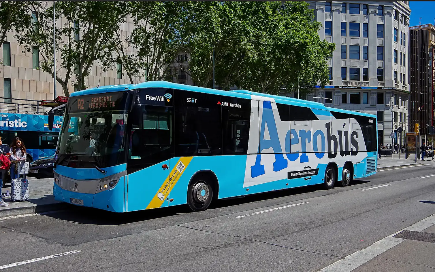 Blue and white bus labeled "Aerobús" parked on a street, offering free WiFi, with buildings and trees in the background.
