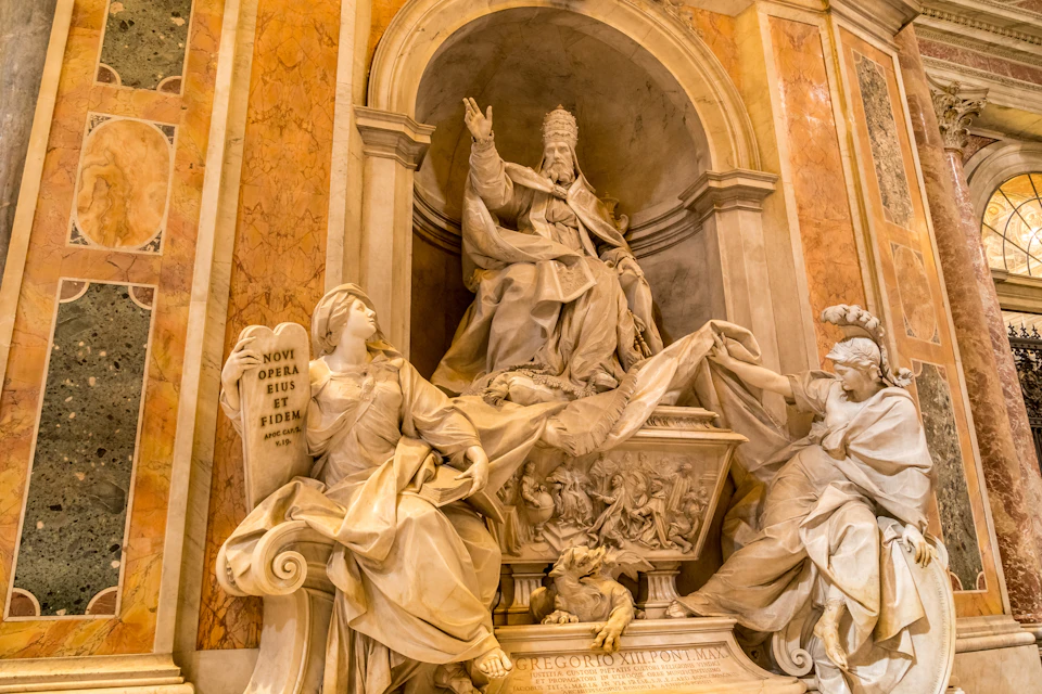 Marble statues featuring a seated figure with a raised hand, surrounded by other figures and intricate carvings in an ornate setting.