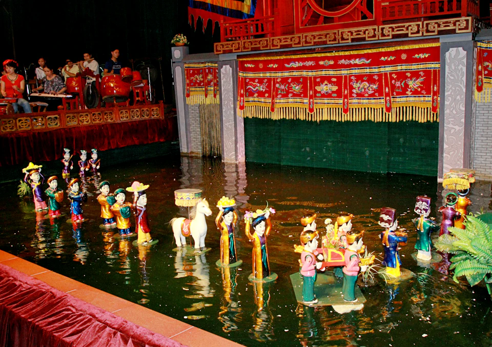 A traditional Vietnamese water puppet performance with puppets on a water stage, colorful costumes, and a red backdrop.