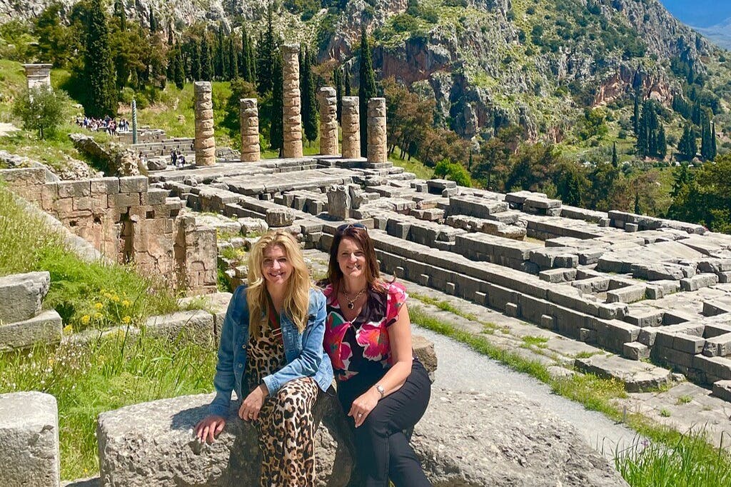 Гости фотографируются с археологическим памятником в Дельфах на заднем плане