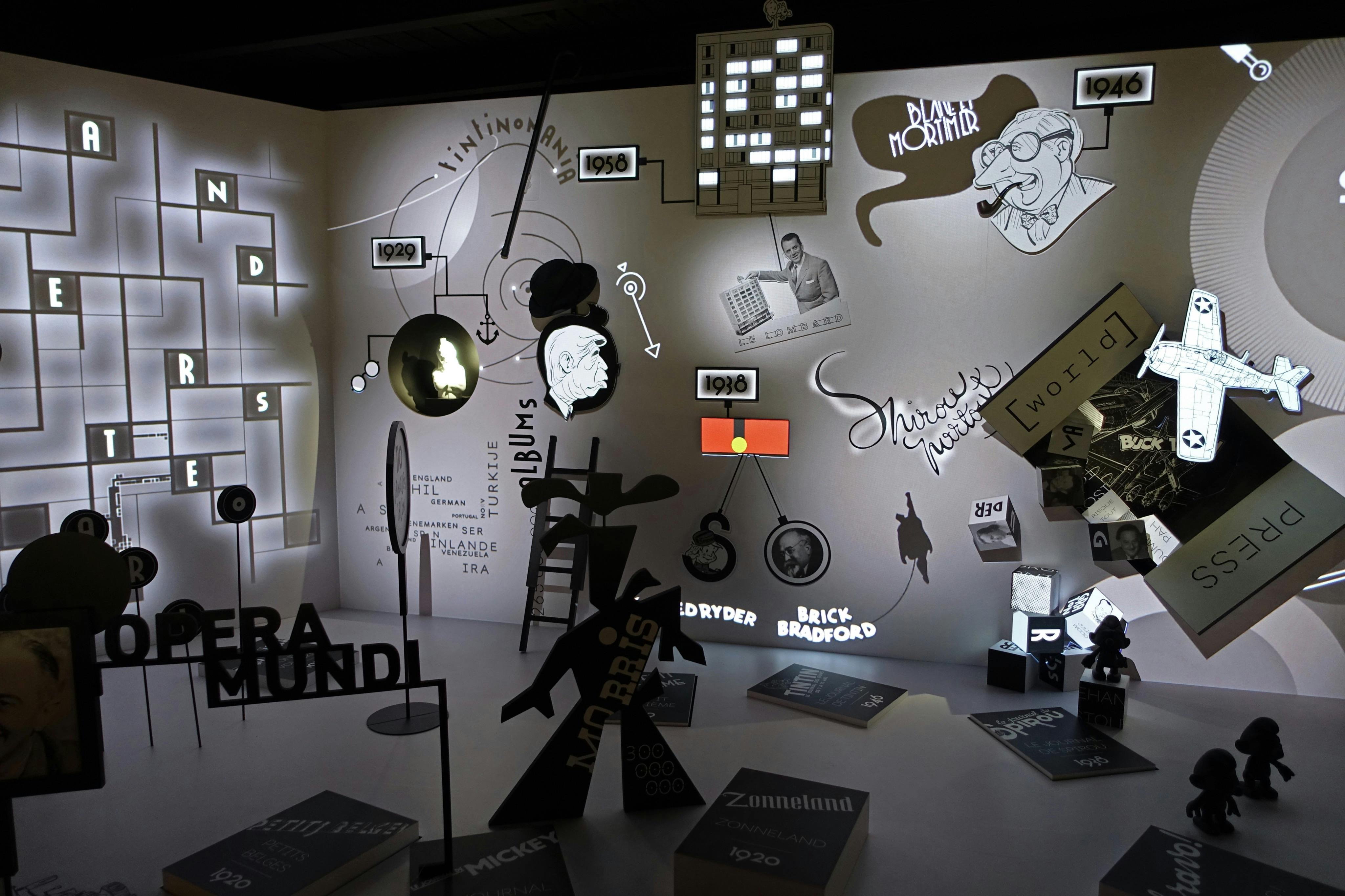 A collage of drawings, timelines, and text in a dimly-lit exhibition space, featuring images and objects from various years and sources.