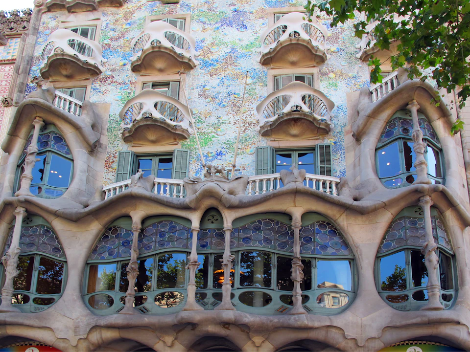 Colorful building façade with organic shapes, ornate balconies, and arched windows.