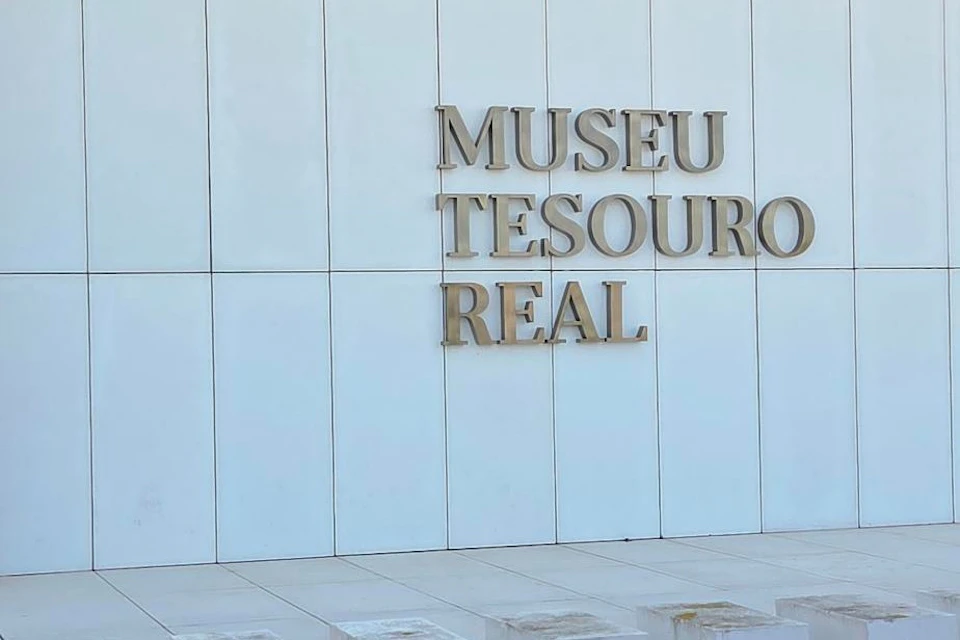 The facade of a building with the text 'Museu Tesouro Real' displayed on a white tiled wall.