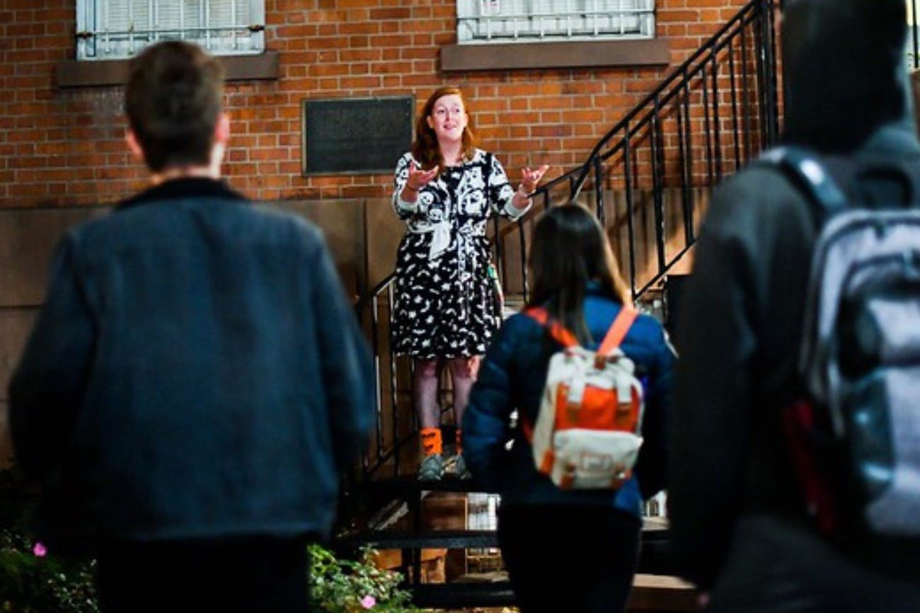 Expressive tour guide telling stories to their group outside of a historic building