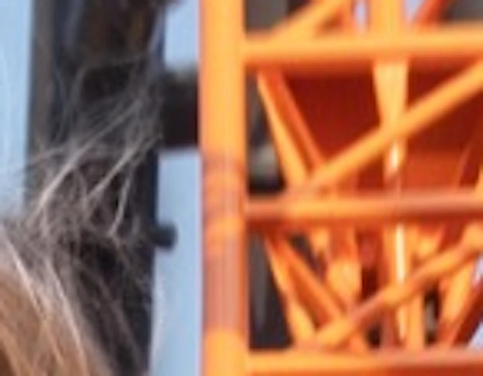 Two people on a rollercoaster ride with orange tracks, appearing thrilled, against a clear blue sky.