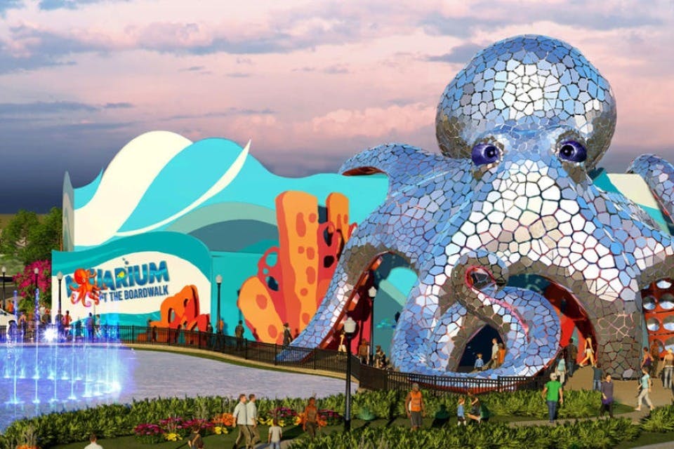 L'entrée colorée d'un aquarium, avec au premier plan une grande sculpture en mosaïque représentant une pieuvre et une fontaine, entourée de visiteurs.