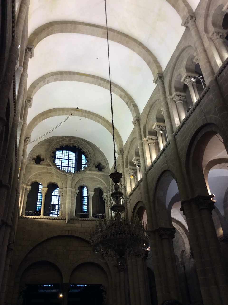 A grand cathedral interior with arched ceilings, large windows, and a central hanging chandelier.