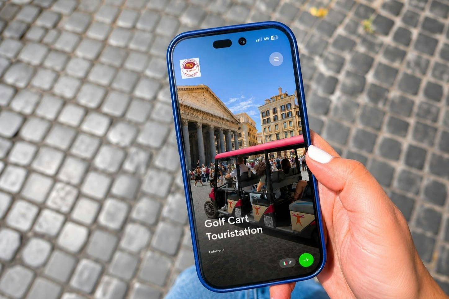 A hand holding a smartphone showing a tour app with an image of a historic building and golf carts in a city square.