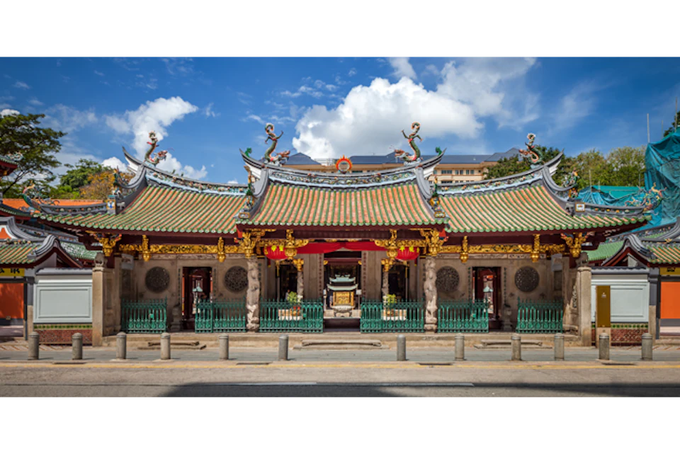Ornate temple with decorative roof, intricate carvings, and red lanterns, under a blue sky with scattered clouds.