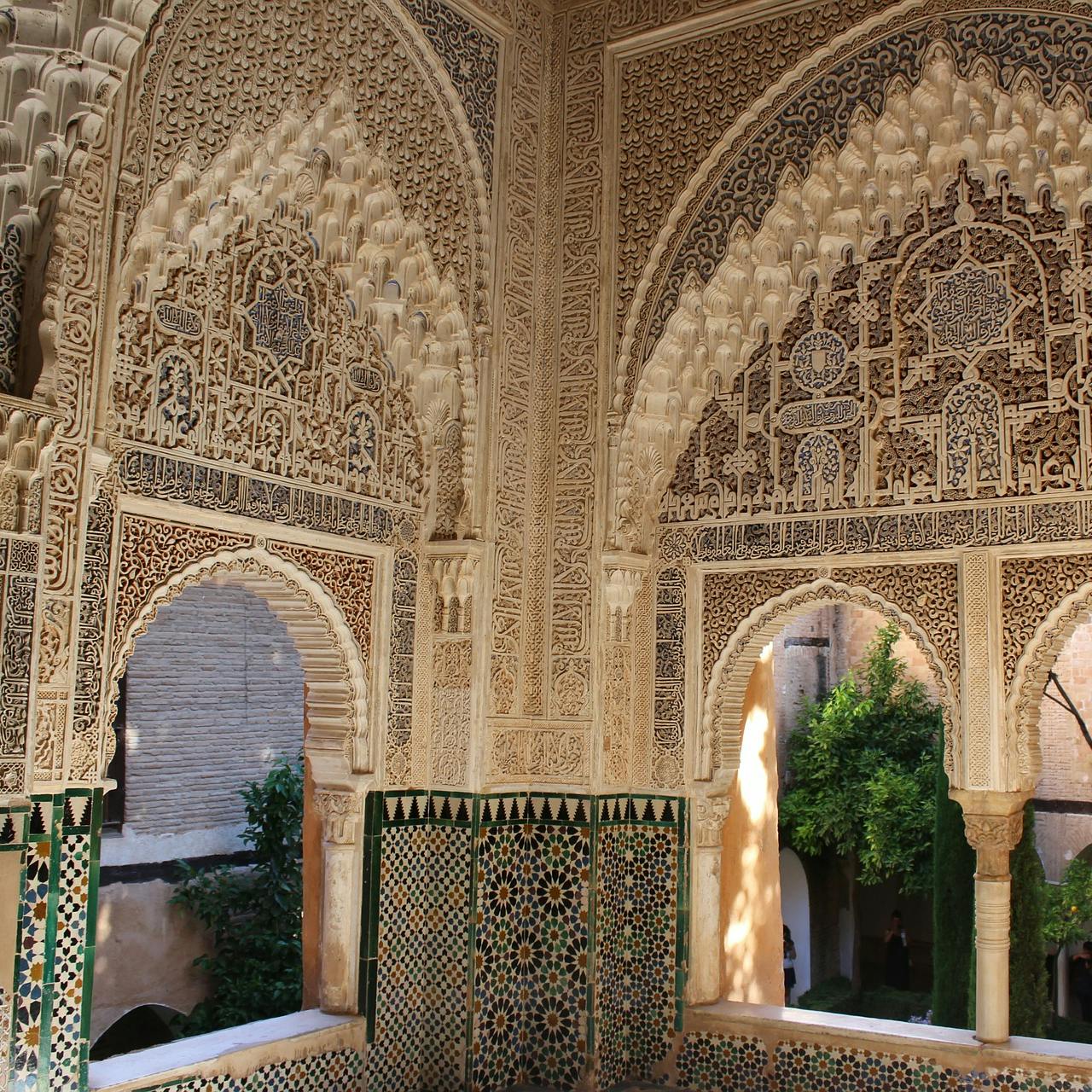 精心雕刻的拱门和墙壁采用传统的伊斯兰建筑风格，配有绿色瓷砖装饰，可欣赏花园美景。