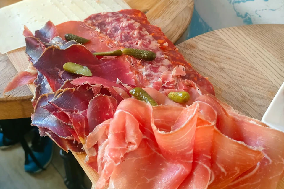 Slices of ham served on a board with pickles