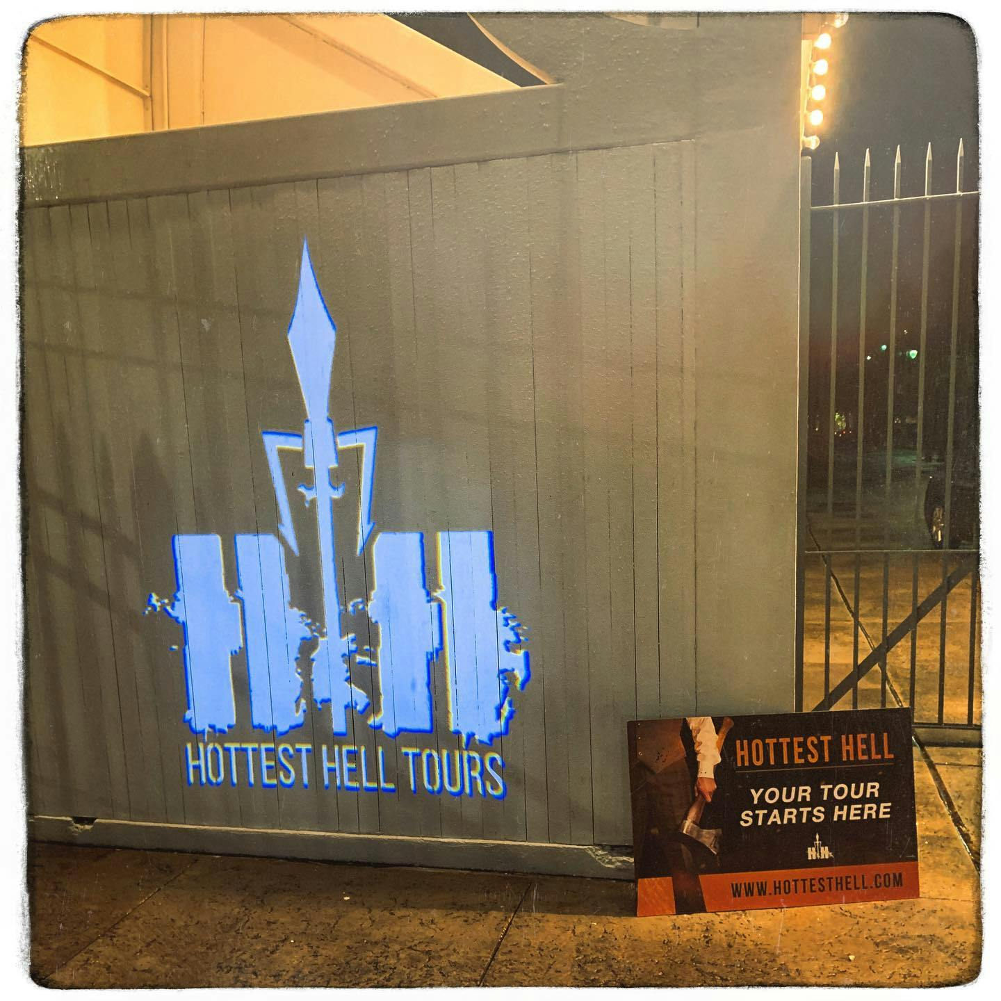 Sign on a gray wall stating "Hottest Hell Tours." Nearby is a poster that reads, "Hottest Hell: Your tour starts here."