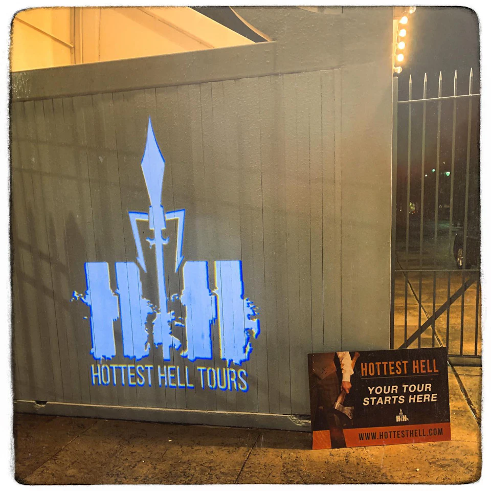 Sign on a gray wall stating "Hottest Hell Tours." Nearby is a poster that reads, "Hottest Hell: Your tour starts here."