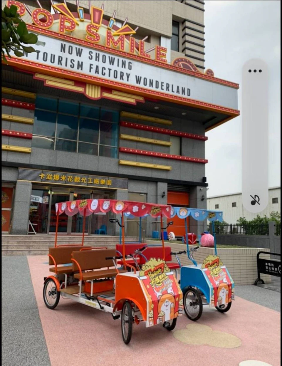 A colorful building labeled 'Tourism Factory Wonderland' with two pedal carriages in front, decorated with banners.