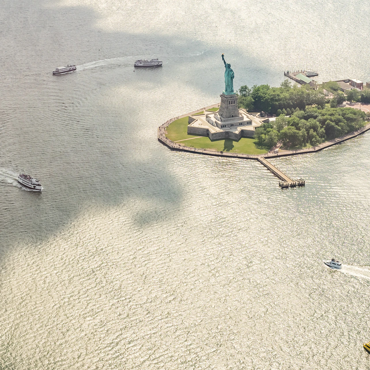 aerial view of ellis island and statue of liberty with ferry boats