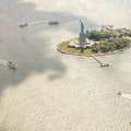 luchtfoto van ellis island en vrijheidsbeeld met veerboten