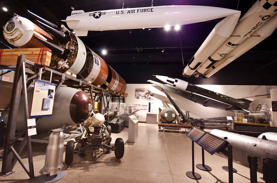 A museum exhibit featuring various military missiles and equipment with a prominent U.S. Air Force missile hanging from the ceiling.