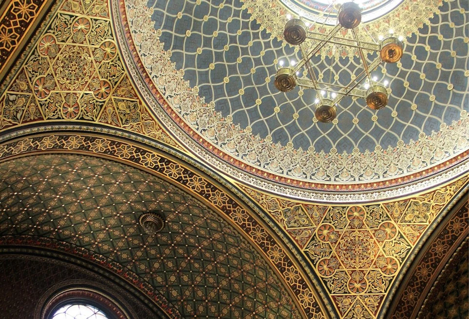 Intricately patterned domed ceiling with gold accents, geometric designs, and a chandelier in the center.