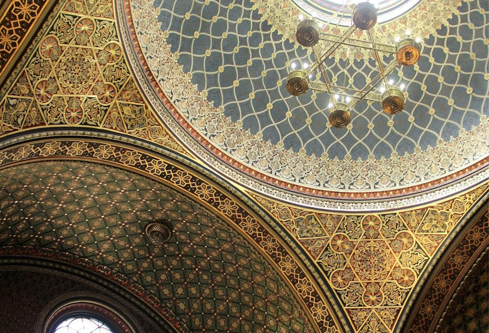 Intricately patterned domed ceiling with gold accents, geometric designs, and a chandelier in the center.