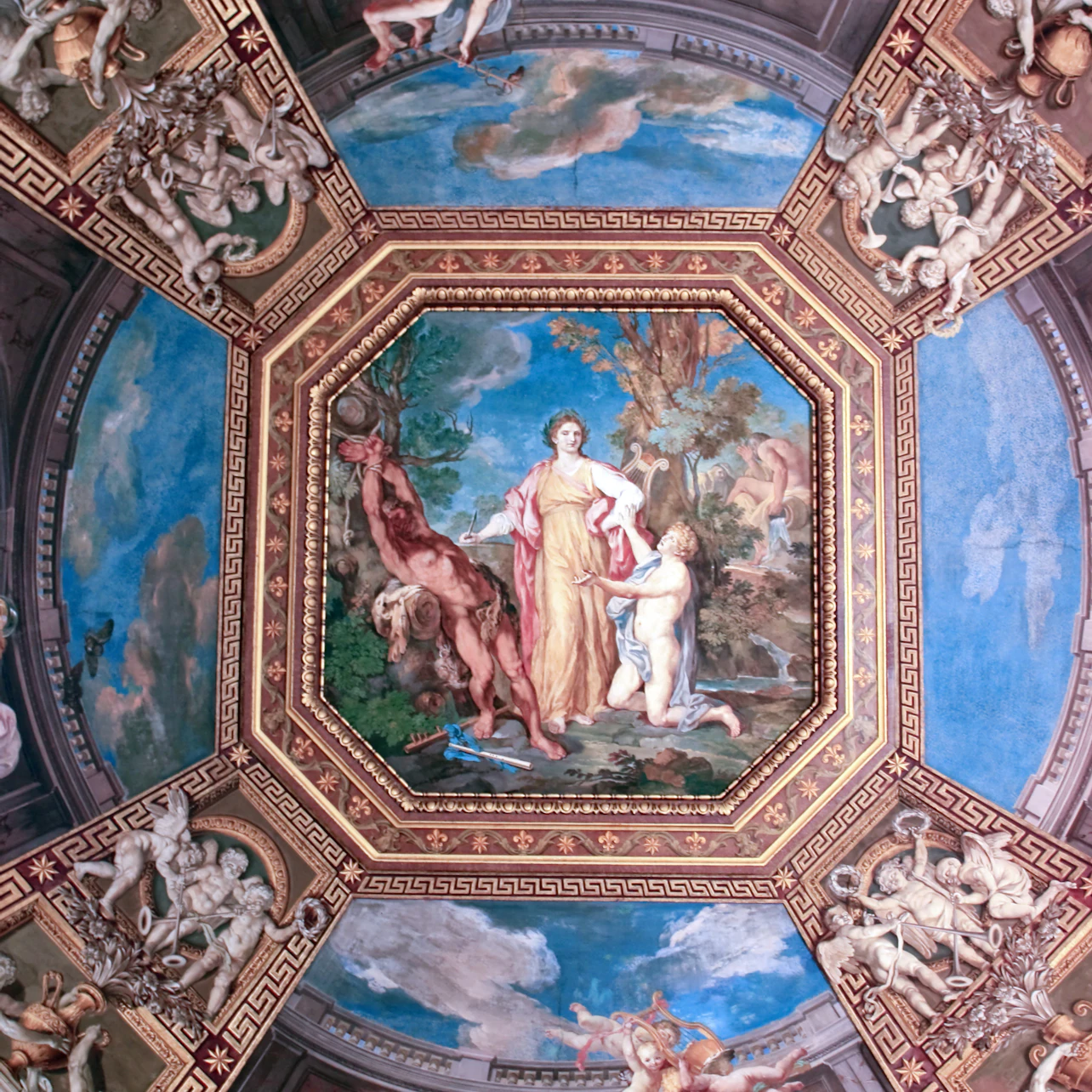 Ornate ceiling fresco depicting mythological figures, surrounded by intricate architectural detailing and vibrant blue sky background.