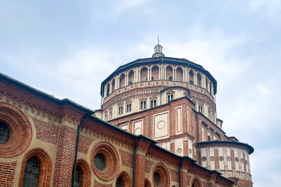 A brick and stone historical building with a domed structure and ornate details under a cloudy sky.