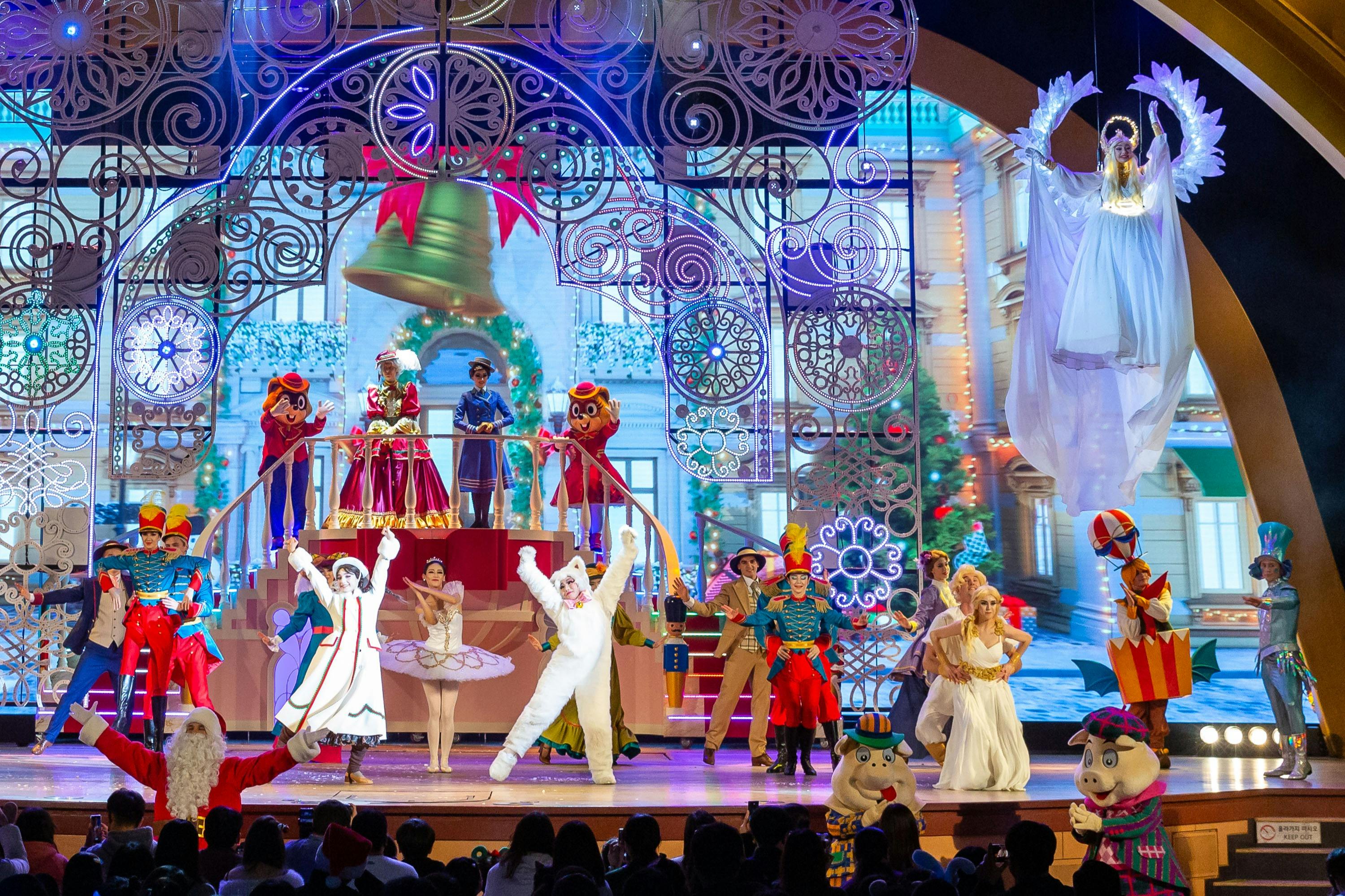 カラフルで気まぐれな衣装を着た多様なパフォーマーのグループが、洗練された装飾を施したステージで踊っています。