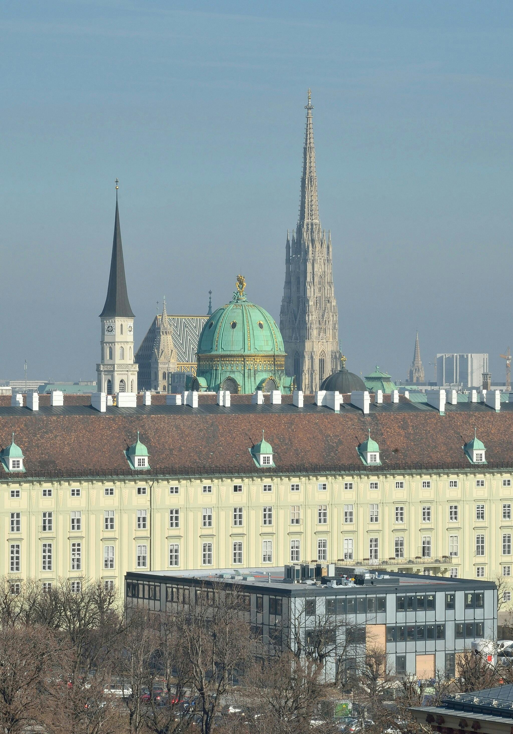 Panoráma města s historickými budovami s kopulemi a věžemi, včetně vysoké gotické katedrální věže.