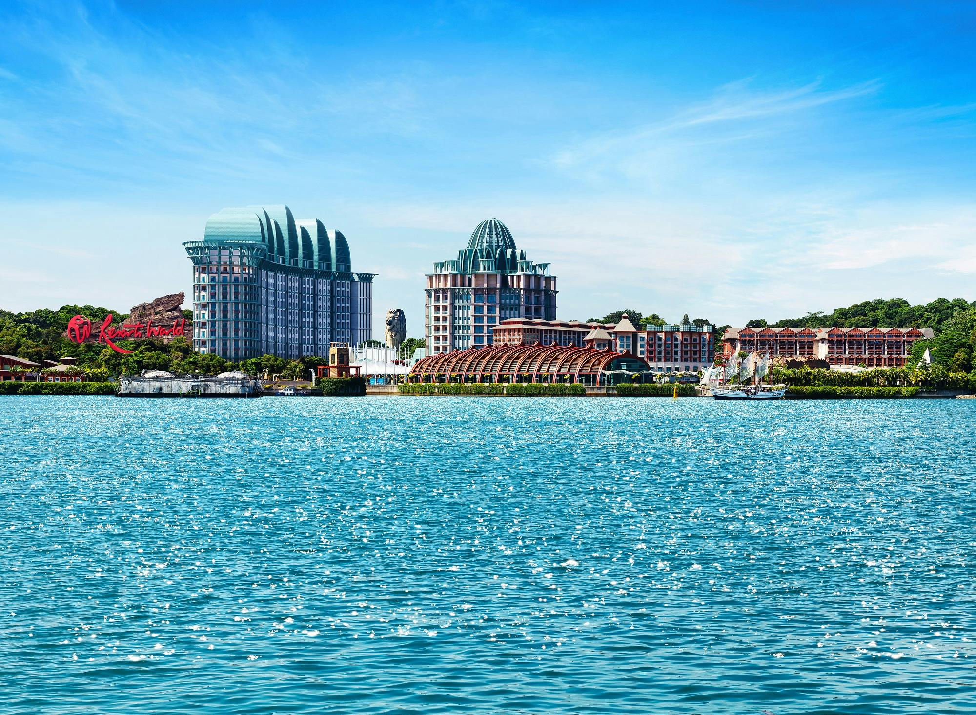 Des bâtiments aux toits en dôme caractéristiques et un front de mer se détachent sur un ciel bleu, avec de l&#39;eau scintillante au premier plan.
